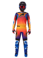 Alpinestars 2025 Fluid Wurx broek, motorcrossbroek, meerkleurig oranje, geel en paars kleurverloop, gedragen met bijpassende jersey, zwarte helm met blauwe crossbril, rood-zwarte handschoenen en blauwe laarzen, gecoördineerde motorcross-race-uitrusting