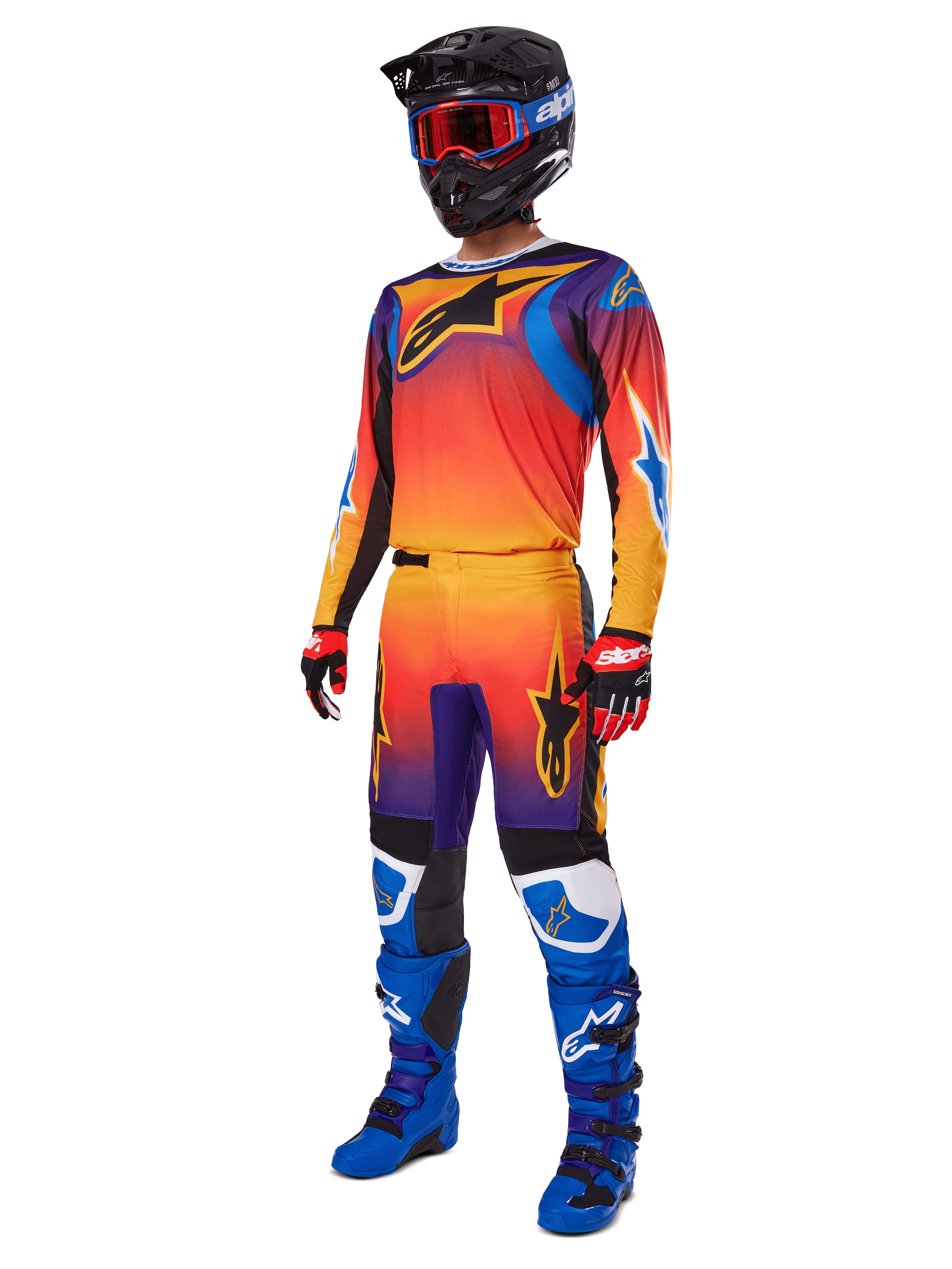Motorcrosser in volledige race-uitrusting, Alpinestars 2025 Fluid Wurx broek en bijpassende jersey met een multicolor verloop van oranje, rood en paars, zwarte helm met rode crossbril, blauwe en zwarte laarzen, rode en zwarte handschoenen, gecoördineerde outfit voor off-road racing