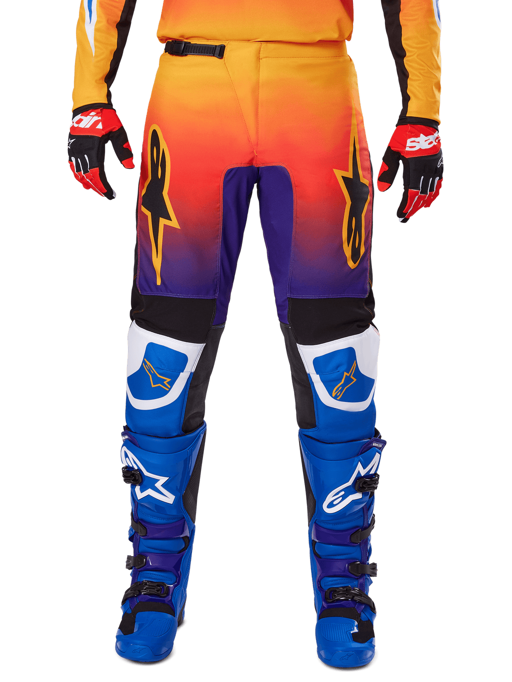 Alpinestars 2025 Fluid Wurx broek, motorcrossbroek, multicolor met een kleurverloop van oranje naar paars en blauwe panelen, gedragen met bijpassende blauwe en paarse laarzen en rood-zwarte handschoenen, vooraanzicht met sterlogo.