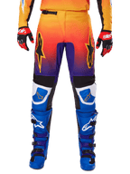 Alpinestars 2025 Fluid Wurx broek, motorcrossbroek, multicolor met een kleurverloop van oranje naar paars en blauwe panelen, gedragen met bijpassende blauwe en paarse laarzen en rood-zwarte handschoenen, vooraanzicht met sterlogo.
