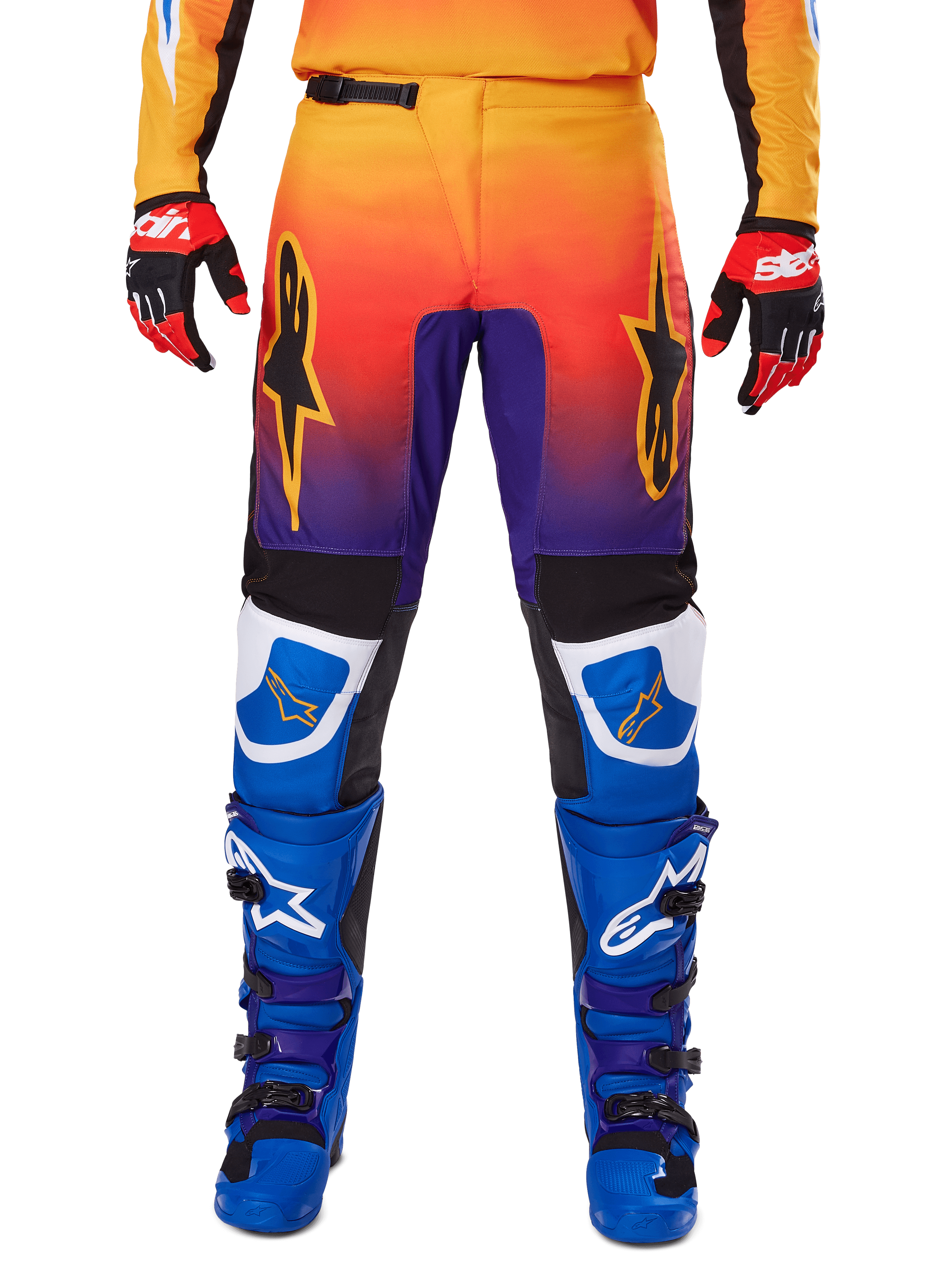 Alpinestars 2025 Fluid Wurx broek, motorcrossbroek, multicolor met een kleurverloop van oranje naar paars en blauwe panelen, gedragen met bijpassende blauwe en paarse laarzen en rood-zwarte handschoenen, vooraanzicht met sterlogo.