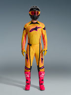 Motocross rider wearing full Alpinestars 2026 Techstar Nomur gear set, Orange Yellow and Pink jersey and pants, matching yellow and pink gloves, vibrant pink racing boots, and black helmet with pink goggles, coordinated high-performance motocross outfit.