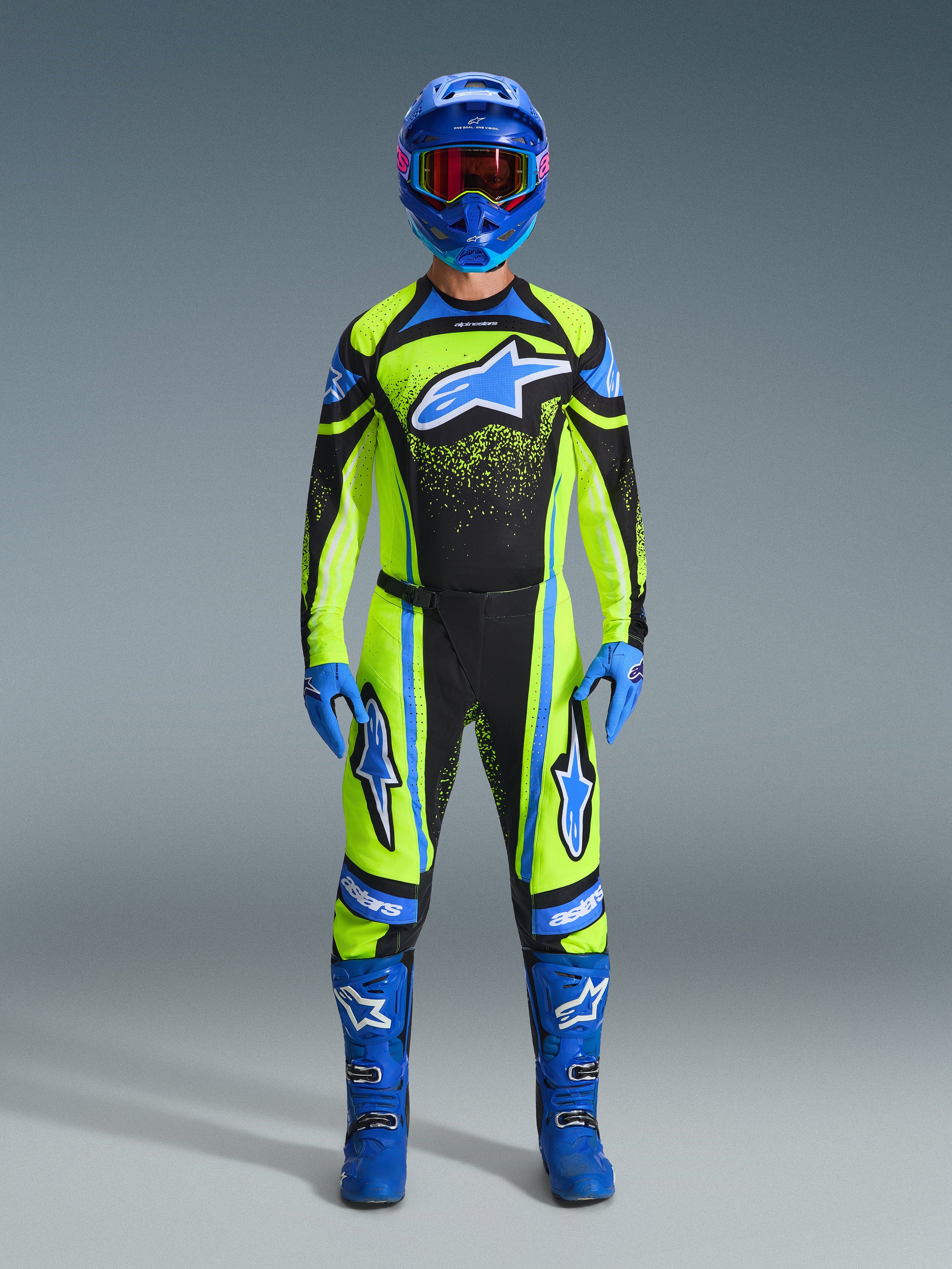 Motocross rider wearing the Alpinestars 2026 Techstar Nomur Gear Set, Fluorescent yellow and black jersey with a large blue star logo, matching yellow and black pants, blue helmet with goggles, blue gloves, and blue boots, complete professional motocross outfit for off-road racing