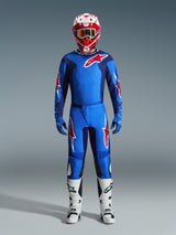 Motocross rider wearing Alpinestars 2026 Fluid Grid Pants in Blue and Red, matching blue jersey with a red Astars logo, red and white helmet with goggles, blue gloves, and white motocross boots, complete coordinated off-road racing gear.