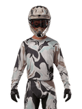 Alpinestars 2024 Racer Tactical Jersey, motocross shirt, Iron Camo Dust Gray camouflagepatroon, rijder met bijpassende helm en crossbril en zwarte handschoenen, technische kleding voor off-road racing