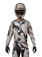 Alpinestars 2024 Racer Tactical Jersey, motocross shirt, Iron Camo Dust Gray camouflagepatroon, rijder met bijpassende helm en crossbril en zwarte handschoenen, technische kleding voor off-road racing