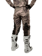 Alpinestars 2024 Racer Tactical crossbroek, motorcross broek, legergroen camouflage bruin, achteraanzicht met camouflagepatroon en zwarte ademende stretchpanelen op de onderbenen, gedragen met witte motorcrosslaarzen, duurzame technische uitrusting voor off-road rijden