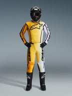 Alpinestars 2026 Fluid Apex Pants, Motocross Pants in Yellow Black and White, worn as a complete racing kit with matching gradient jersey, black helmet, and boots, professional off-road riding gear.