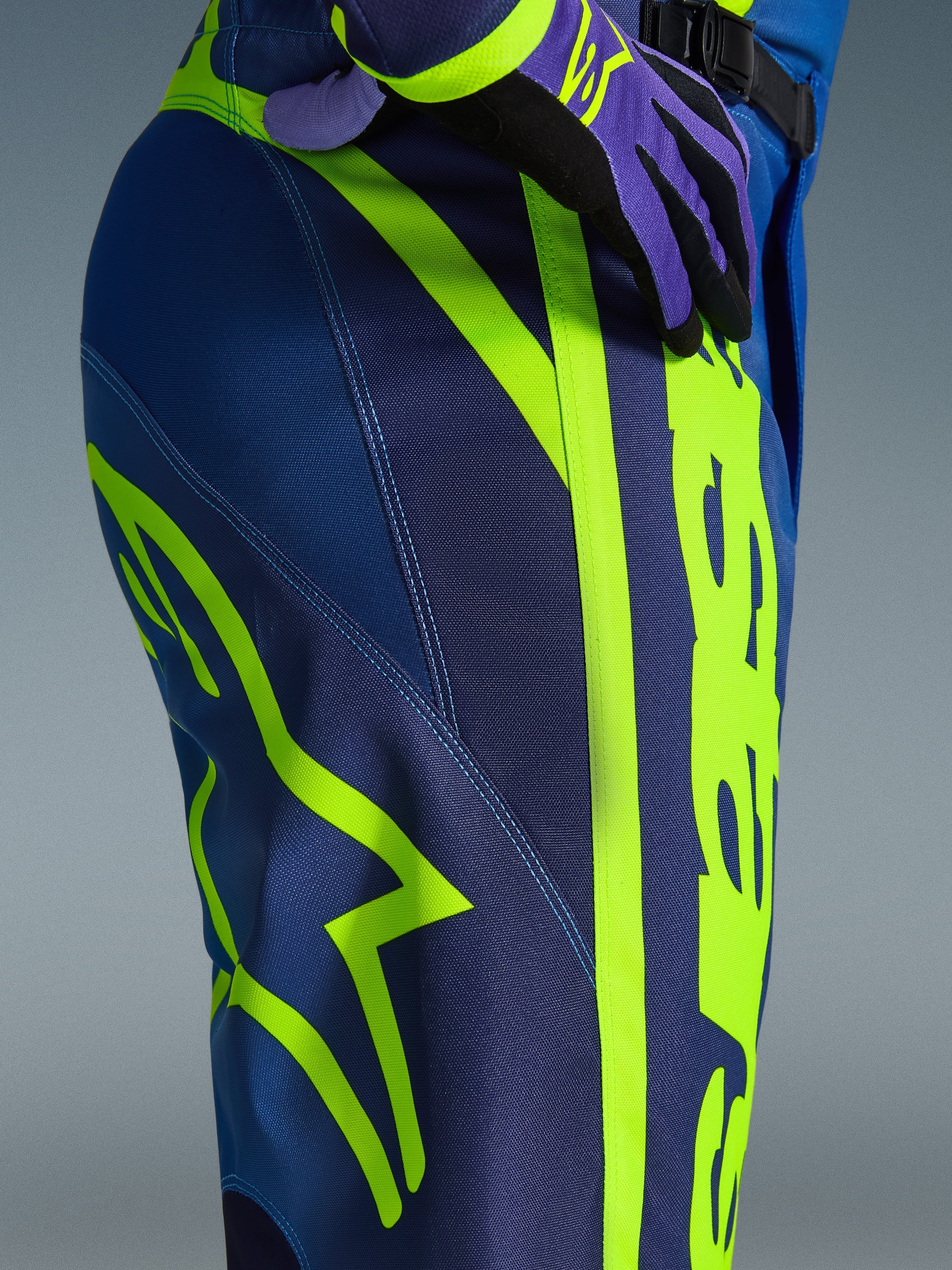 Alpinestars 2026 Fluid Apex Pants, Motocross Pants, Blue and Yellow Fluo, close-up view of the side and hip featuring bold neon yellow Alpinestars branding, durable polyfabric material for off-road riding, part of matching gear set