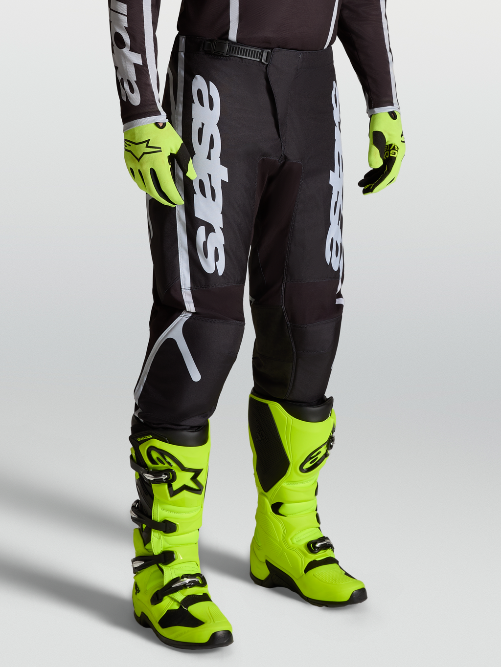 Alpinestars Fluid Apex V2 Broek, heren motocrossbroek in zwart en zilver, model met felgele laarzen en handschoenen.