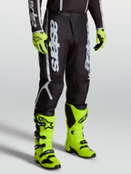 Alpinestars Fluid Apex V2 Broek, heren motocrossbroek in zwart en zilver, model met felgele laarzen en handschoenen.