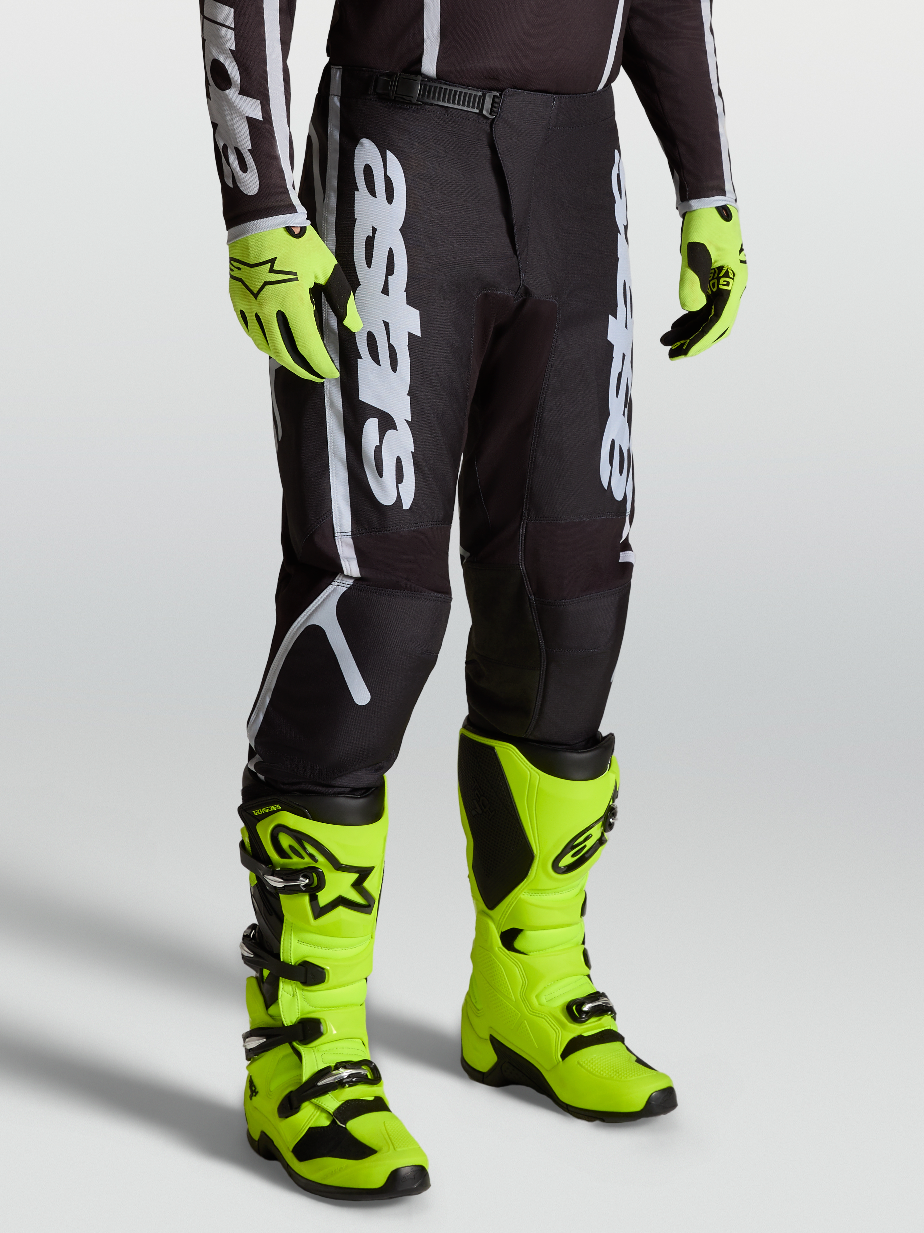 Alpinestars Fluid Apex V2 Broek, heren motocrossbroek in zwart en zilver, model met felgele laarzen en handschoenen.