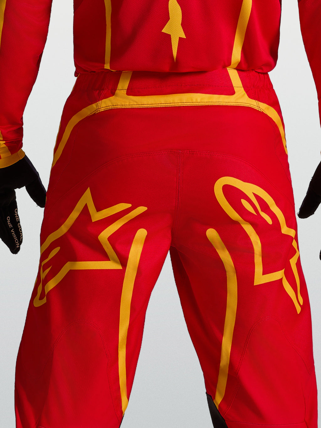 Alpinestars Fluid Apex V2 broek, motocrossbroek in rood en goud, met versterkt rugpand en grote ster-graphics op het zitvlak.