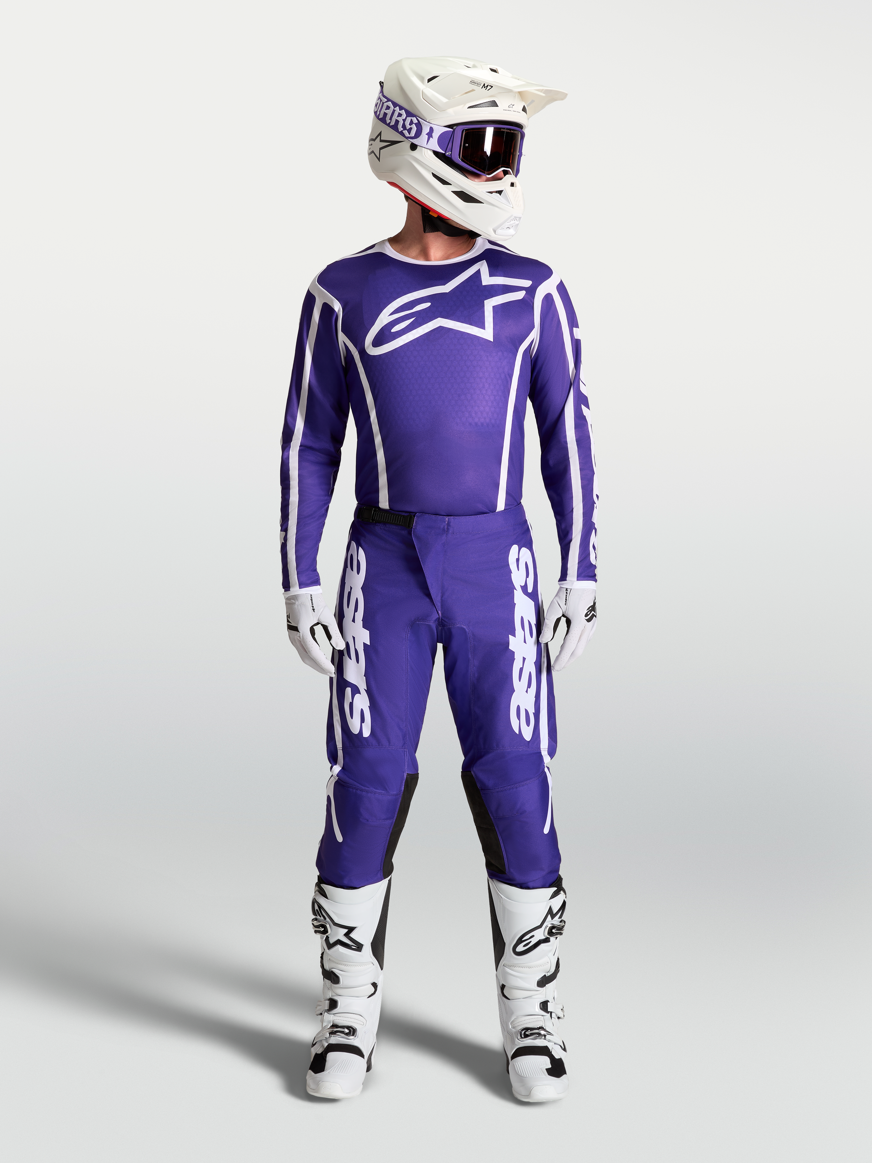 Alpinestars Fluid Apex V2 broek, heren motocrossbroek in donkerblauw en wit, getoond met bijpassende jersey en witte motorlaarzen voor off-road racing.