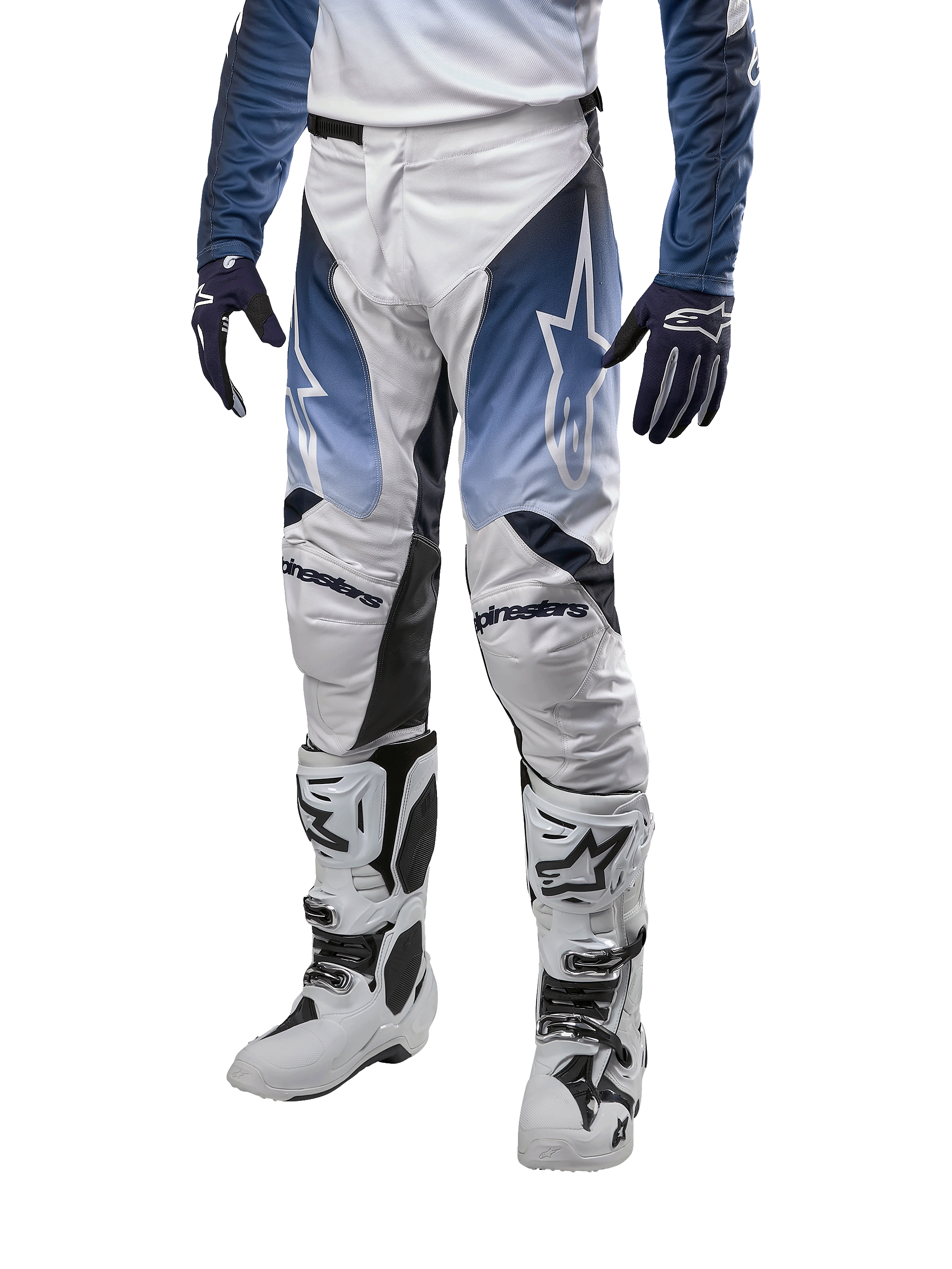 Alpinestars 2024 Racer Hoen motorcrossbroek, wit met donkerblauw en lichtblauw, witte logo's, sportieve pasvorm voor off-road, persoon draagt volledige motorcross uitrusting met witte laarzen en blauwe handschoenen