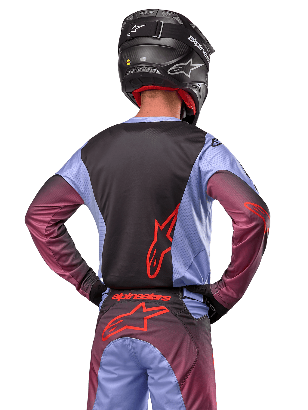 Motorcrossrijder van achteren in Alpinestars 2024 Racer Hoen uitrusting, Lavan Purple en zwart jersey met rood logo, bijpassende broek met rode accenten, zwarte helm, gecoördineerde outfit voor off-road racen
