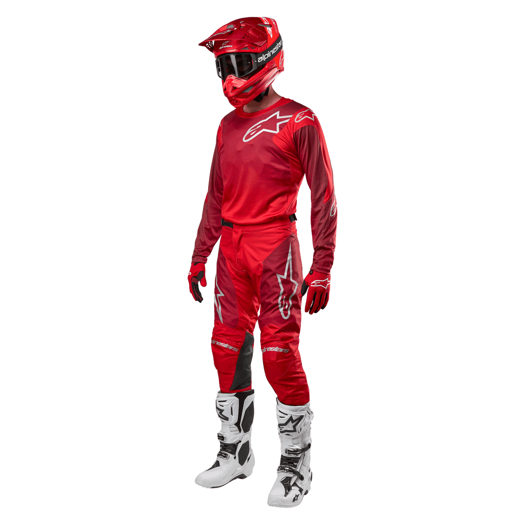 Motorcrosser in volledige race-uitrusting, Alpinestars 2024 Racer Hoen broek en jersey in Mars Red Burgundy, rode helm, rode handschoenen en witte en zwarte laarzen, gecoördineerde outfit voor off-road rijden