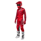 Motorcrosser in volledige race-uitrusting, Alpinestars 2024 Racer Hoen broek en jersey in Mars Red Burgundy, rode helm, rode handschoenen en witte en zwarte laarzen, gecoördineerde outfit voor off-road rijden