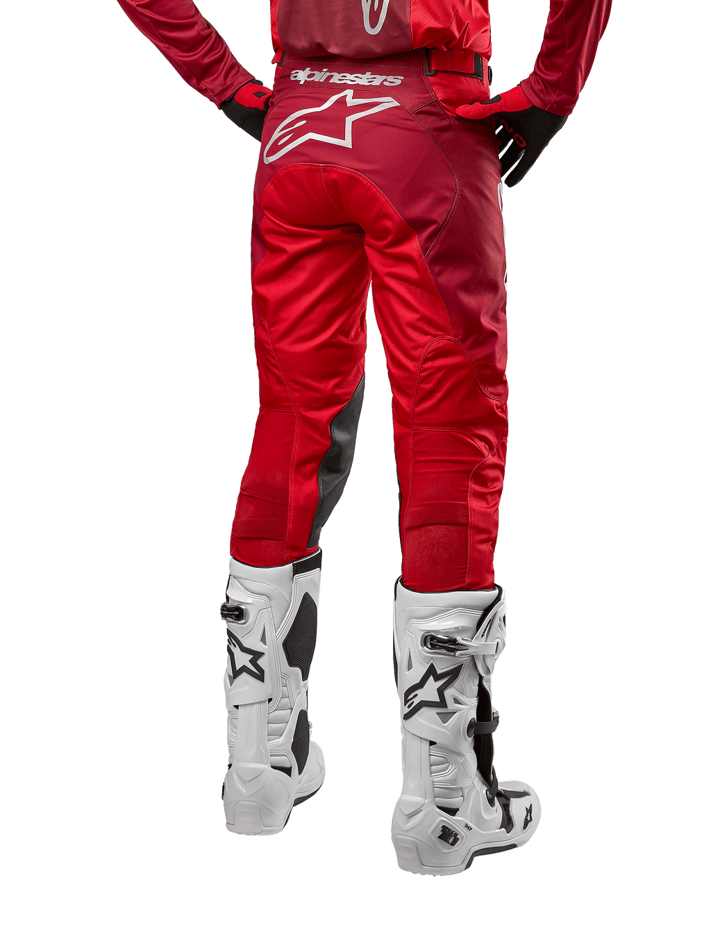Alpinestars 2024 Racer Hoen broek, motorcrossbroek, Mars Red Burgundy, achteraanzicht met een groot wit Astar-logo op de achterzijde, zwarte kniepanelen aan de binnenzijde, gedragen met witte motorcrosslaarzen, hoogwaardige off-road uitrusting