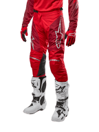 Alpinestars 2024 Racer Hoen crossbroek, motorcross broek, Mars Red en Burgundy, gedragen met bijpassende rode jersey en handschoenen en witte laarzen, met zwarte leren kniepanelen en witte logo's, duurzame technische kleding voor off-road racing