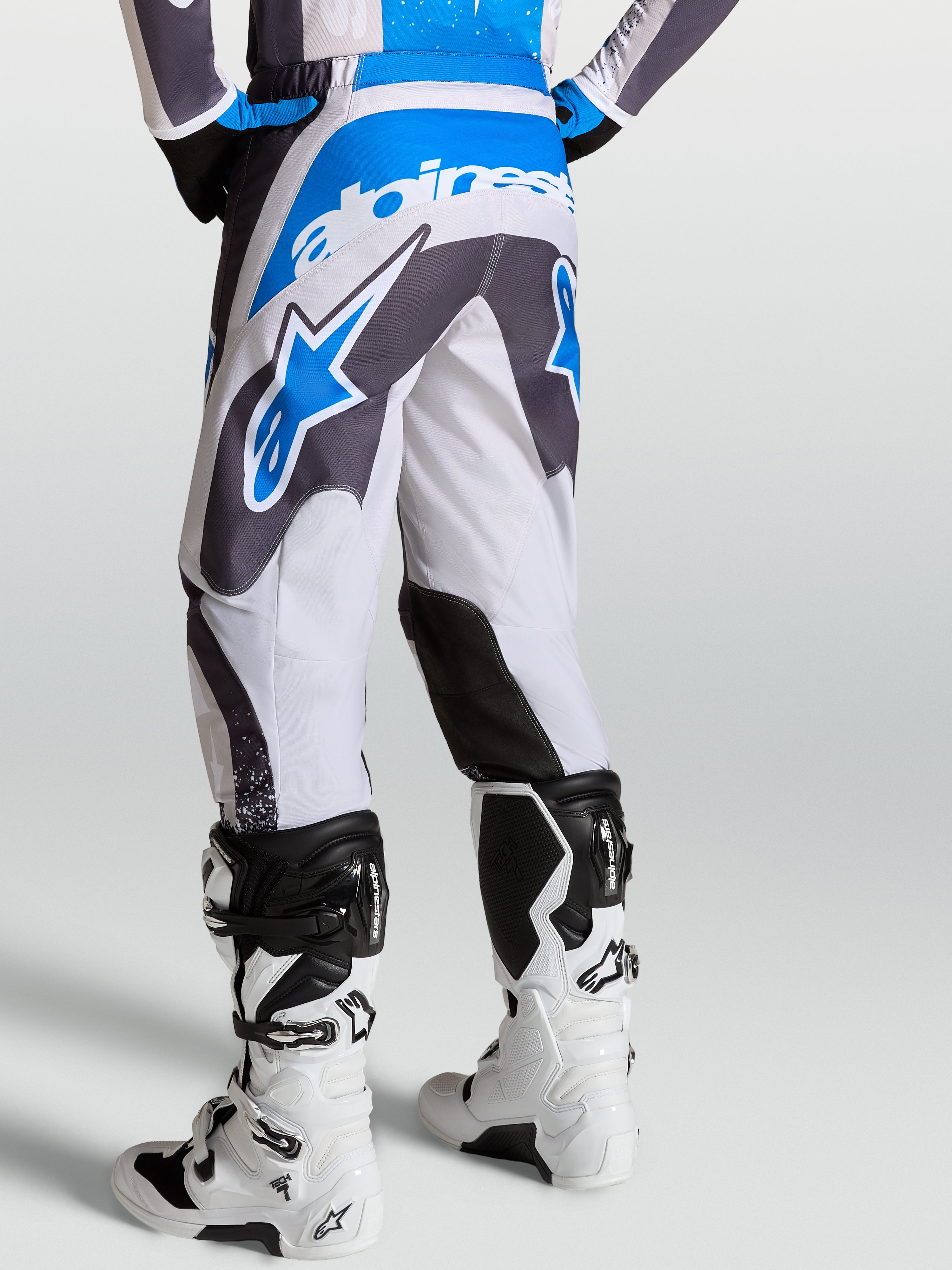 Alpinestars Fluid Drag broek, heren motocrossbroek in grijs en blauw, achteraanzicht met ergonomische 3D-patroonconstructie.