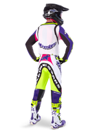Alpinestars Limited Edition Supertech Dirt Studios® crossbroek in White Purple en Yellow Fluo, motocrossrijder vanaf de achterkant gezien met bijpassende jersey, laarzen en zwarte carbon helm, professionele off-road race-uitrusting met opvallende graphics en neonaccenten.