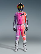 Alpinestars 2026 Racer Air Portl Jersey en bijpassende broek, motocrosser in uitrusting met roze, paars en oranje kleurverloop, zwarte Alpinestars logo's, witte motorlaarzen, zwarte handschoenen en een multicolor helm, professionele off-road race-uitrusting