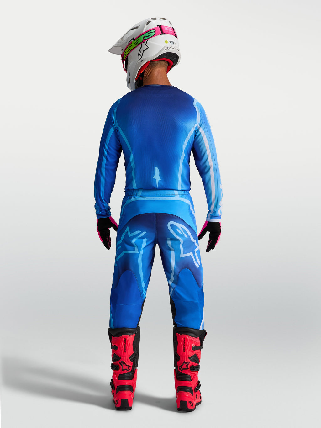 Alpinestars Fluid Kepler Broek, heren motorcrossbroek in UCLA blauw, achteraanzicht met ergonomische pasvorm en duurzame polystof, gedragen met rode laarzen voor off-road racing.