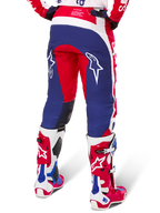 Alpinestars Limited Edition Techstar Fortitude broek, motorcrossbroek, rood, wit en blauw, achteraanzicht gedragen met bijpassende rode en witte laarzen, voorzien van witte sterlogo's op de dijen, duurzaam meerpaneel-ontwerp voor professioneel off-road racen.