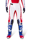 Limited Edition Techstar Fortitude crossbroek, motorcross broek, felrood, wit en blauw, gedragen met bijpassende uitrusting waaronder blauwe beschermende laarzen en handschoenen, voorzien van een wit chassis met rode graphics, zwarte leren kniepanelen en lasergesneden perforaties, professionele off-road racekleding