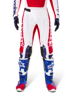 Limited Edition Techstar Fortitude crossbroek, motorcross broek, felrood, wit en blauw, gedragen met bijpassende uitrusting waaronder blauwe beschermende laarzen en handschoenen, voorzien van een wit chassis met rode graphics, zwarte leren kniepanelen en lasergesneden perforaties, professionele off-road racekleding