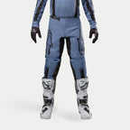 Alpinestars 2024 Fluid Lurv crossbroek, motorcross broek, lichtblauw en zwart, gedragen met witte en zwarte racelaarzen en bijpassende handschoenen, voorzien van opvallende zwarte sterlogo's op de dijen, ergonomisch ontwerp voor off-road prestaties
