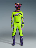 Motocross rider wearing the Alpinestars 2026 Supertech Vista Jersey in bright yellow with purple and black accents, matching yellow and purple pants, purple boots, and coordinated helmet and gloves, complete professional racing gear set