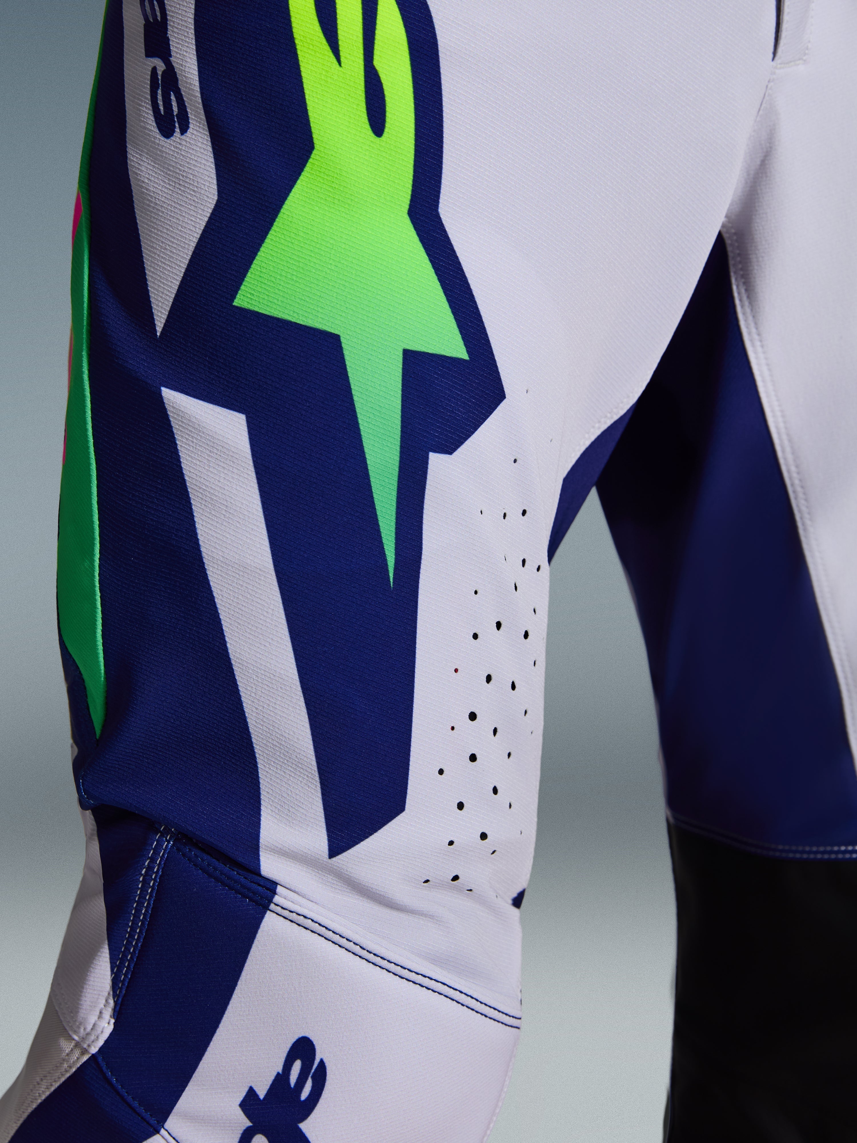Alpinestars 2026 Supertech Vista Pants, Motocross Pants, Light Gray with Yellow Fluo and Blue accents, close-up view of the thigh showing the large A-star logo, laser-cut ventilation holes, and advanced stretch rip-stop fabric.