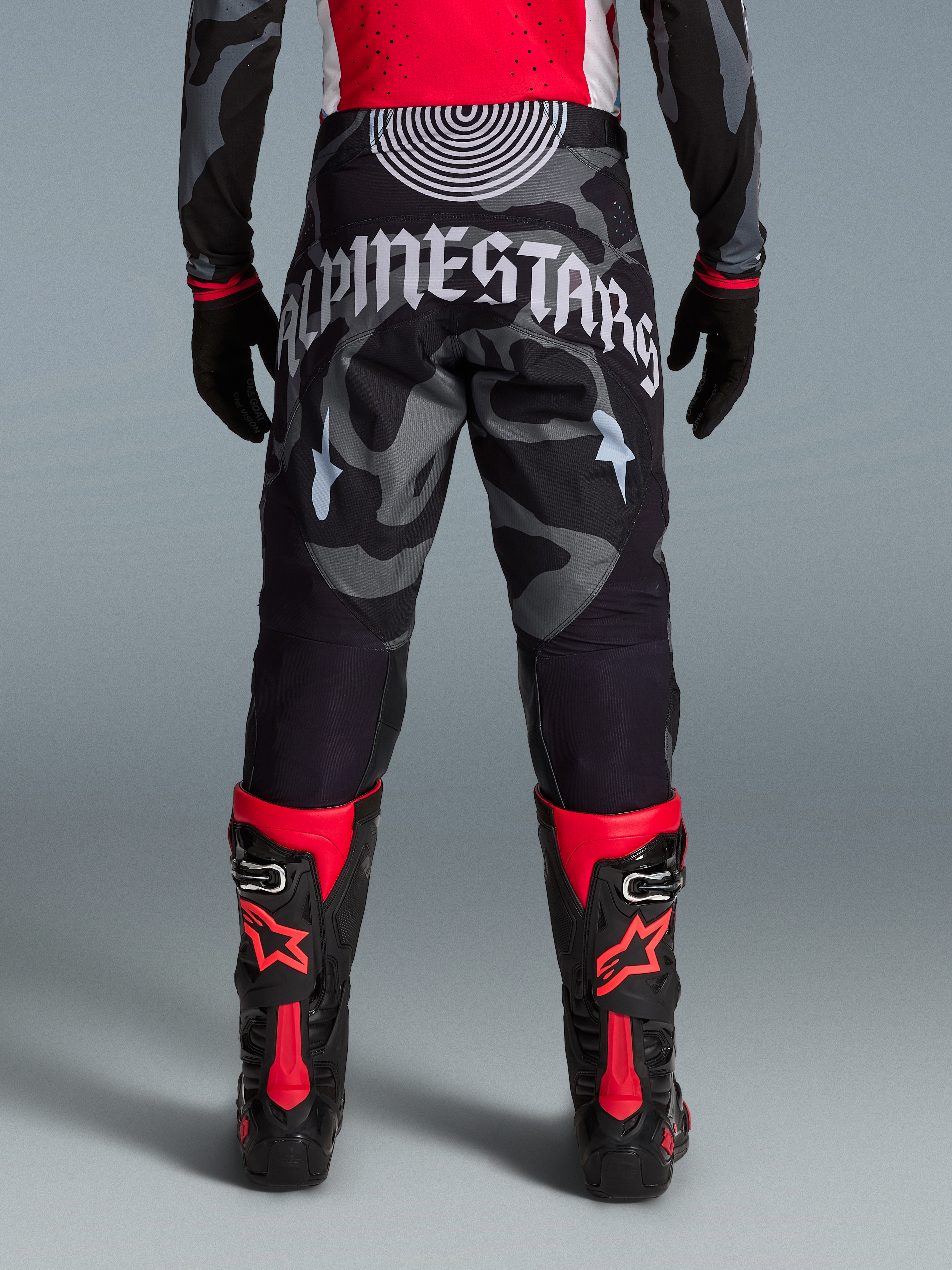Techstar Beast Coast broek in grijs camouflage met groot wit Alpinestars-logo op de achterzijde en rode motorlaarzen.