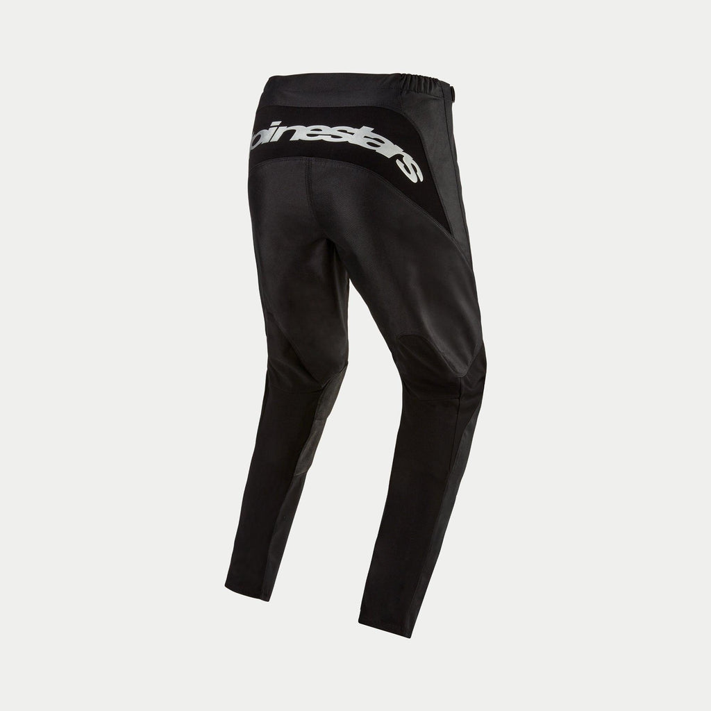 Alpinestars 2024 Fluid Graphite broek, motorcross broek, zwart en zilver, achteraanzicht met zilveren Alpinestars-logo op de achterpas, sportief ontwerp met versterkte panelen, duurzame poly-stof voor off-road racen