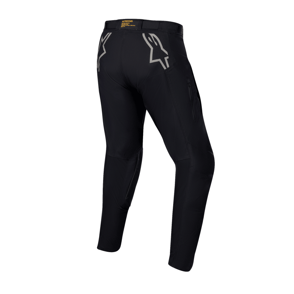 Alpinestars Techdura broek, zwarte enduro- en off-roadbroek, achteraanzicht met grijze sterlogo's op de heupen en gele branding op de achterkant van de tailleband, robuust stretch polyamide materiaal, duurzaam ontwerp voor motorrijden
