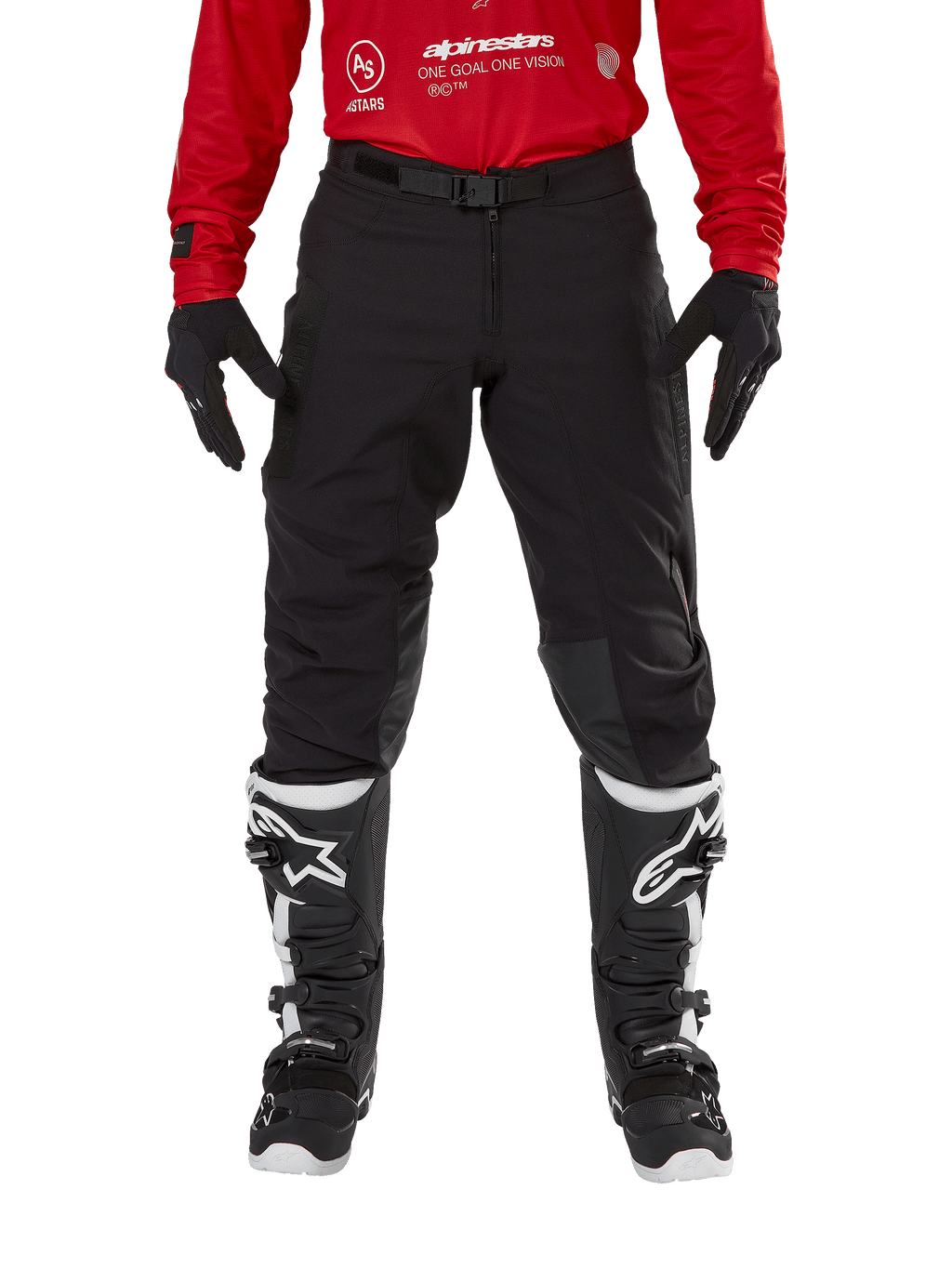 Alpinestars Techdura broek, enduro- en off-roadbroek, zwart, gedragen met een rood Alpinestars shirt en zwart-witte laarzen, voorzien van een robuuste stretch canvas constructie, verstelbare magnetische riemgesp en leren knieverstevigingen voor off-road prestaties.