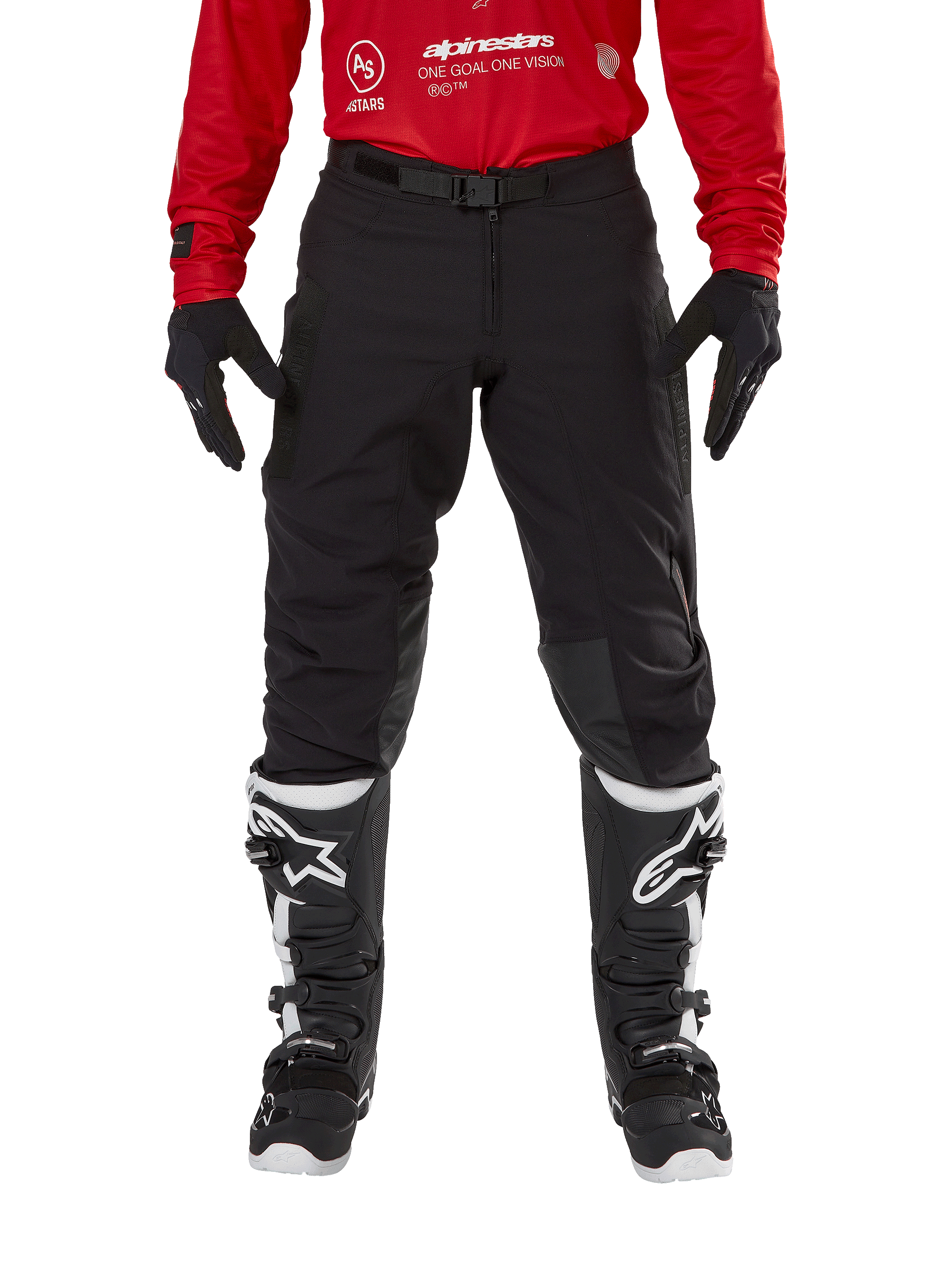 Alpinestars Techdura broek, enduro- en off-roadbroek, zwart, gedragen met een rood Alpinestars shirt en zwart-witte laarzen, voorzien van een robuuste stretch canvas constructie, verstelbare magnetische riemgesp en leren knieverstevigingen voor off-road prestaties.