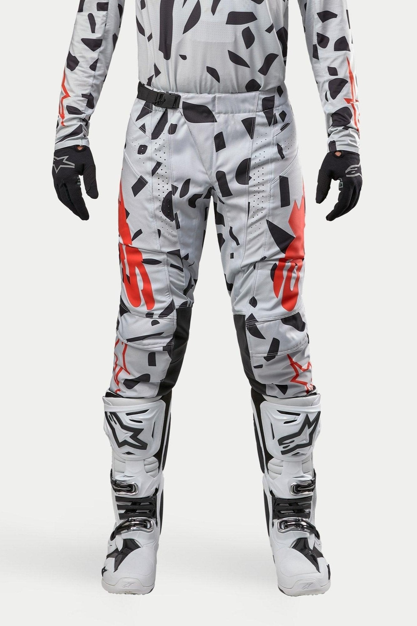 Alpinestars 2024 Techstar Rantera broek, motorcrossbroek, Haze Gray Camo, gedragen met bijpassende jersey, zwarte handschoenen en witte laarzen, voorzien van zwart vlekkenpatroon en rode Alpinestars-branding, duurzaam ontwerp voor off-road racen