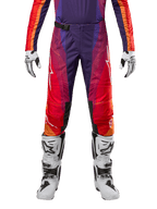 Alpinestars 2024 Techstar Pneuma crossbroek, motorcross broek in dieppaars, oranje en diepblauw, witte logo's op de benen, SX2 magnetische gesp, gedragen met witte crosslaarzen en bijpassende handschoenen