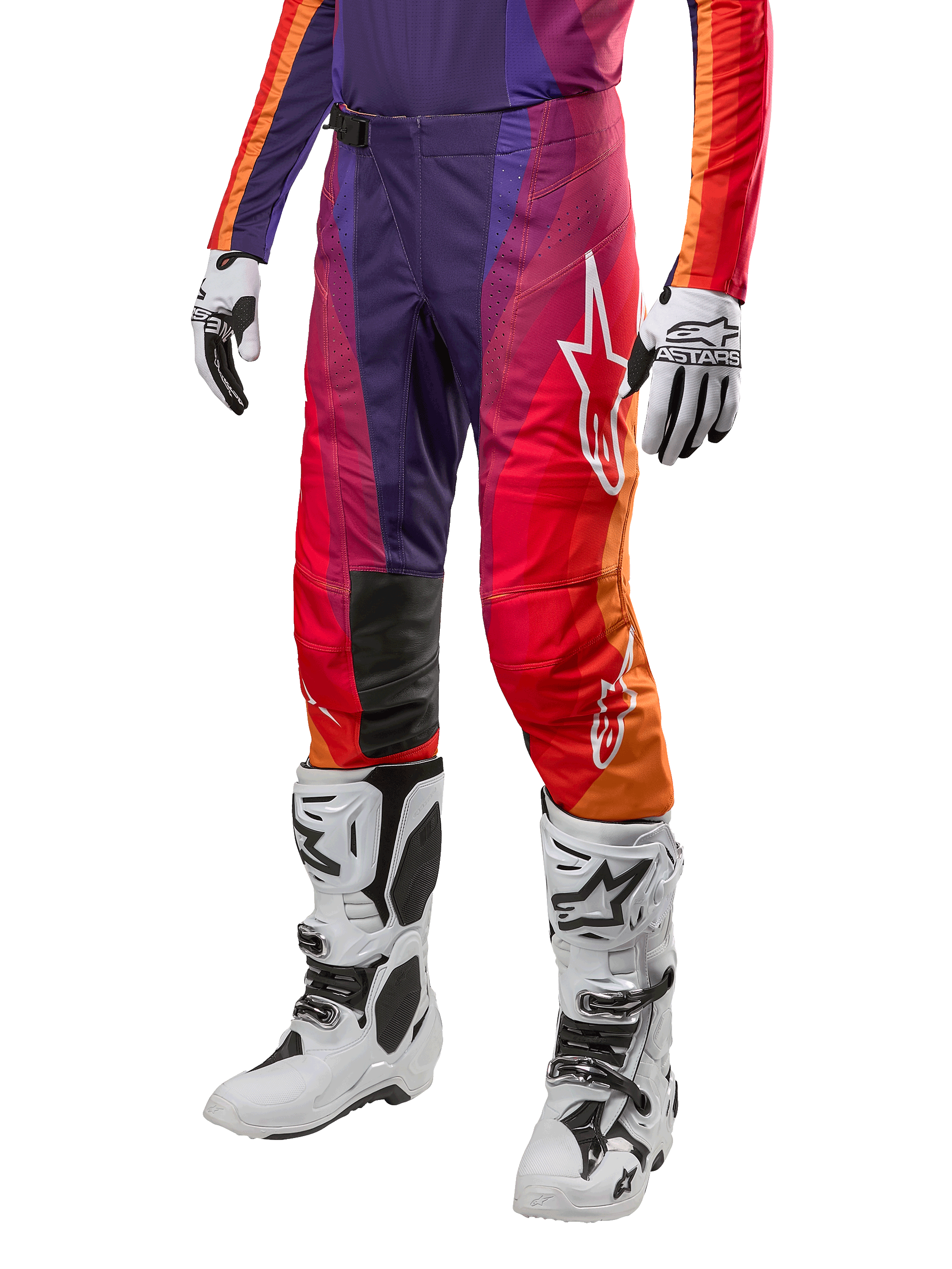 Alpinestars 2024 Techstar Pneuma crossbroek, motorcross broek, paars met oranje en blauw kleurverloop, witte logo's, persoon draagt de broek in combinatie met witte motorcrosslaarzen en handschoenen, sportieve off-road uitrusting