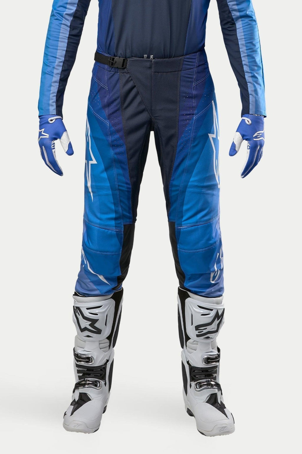 Alpinestars 2024 Techstar Pneuma crossbroek, motorcross broek, donkerblauw en lichtblauw, gedragen met bijpassende blauwe jersey en witte laarzen, voorzien van witte Alpinestars-branding en magnetische gespsluiting, ontworpen voor professionele off-road prestaties