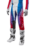 Alpinestars 2024 Techstar Pneuma broek, motorcross crossbroek, rood, blauw en wit, gedragen met bijpassende jersey, witte racelaarzen en handschoenen, levendig grafisch ontwerp met rode, blauwe en paarse accenten, geperforeerd voor ademend vermogen