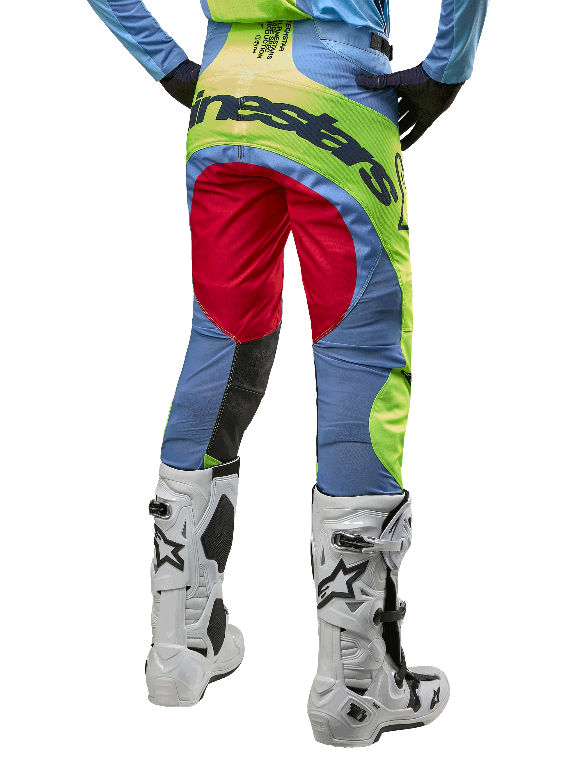 Alpinestars 2024 Techstar Ocuri crossbroek, motorcrossbroek, lichtblauw met fluogeel en bessenrood, achteraanzicht gedragen met witte en zwarte motorcrosslaarzen, voorzien van opvallende kleurvlakken en een groot Alpinestars-logo op het zitvlak