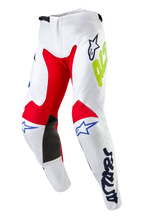 Alpinestars 2024 Racer Hana crossbroek, motorcross broek, wit multicolor, met rode en zwarte panelen aan de binnenzijde van de knieën, blauwe Astars-logo's en neongele branding, voorgevormd ontwerp met ratelsluiting in de taille, duurzame textieluitrusting voor off-road