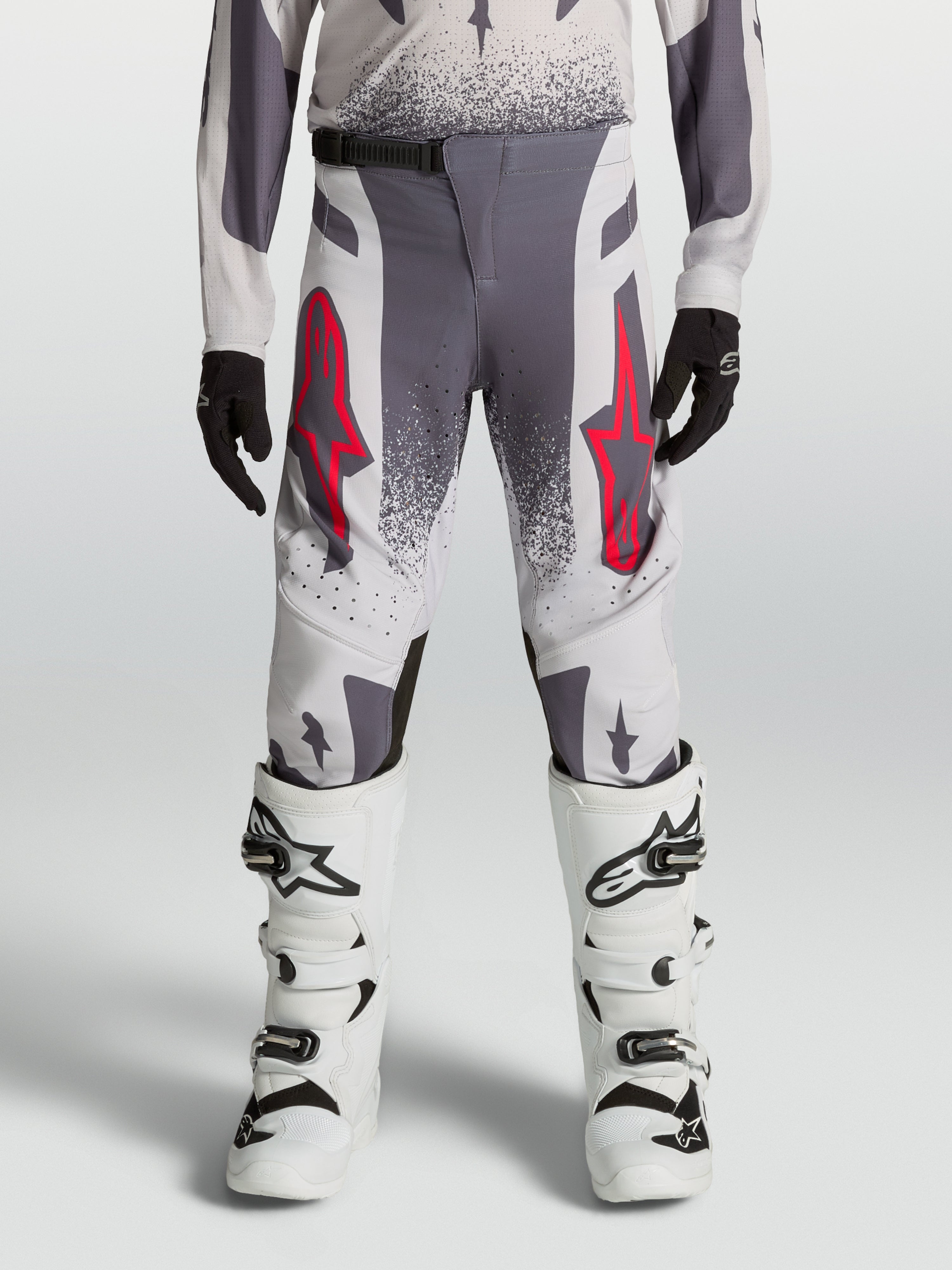 Alpinestars Jeugd Supertech Swan broek 2027, grijze en lila motocross-racebroek met rode accenten en witte motorlaarzen.