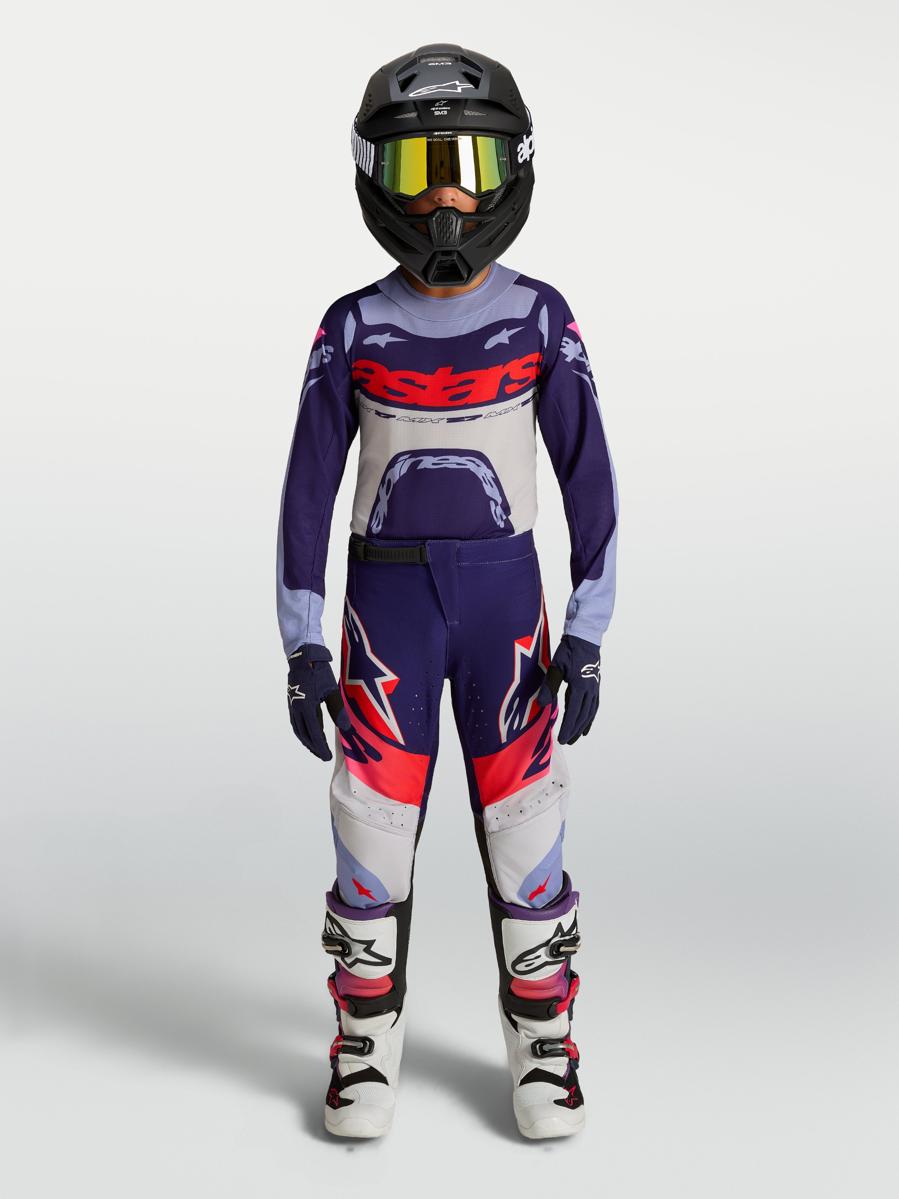 Alpinestars jeugd Supertech Dyna motorcrossbroek, paars en roze fluo, gedragen door model voor off-road racing.