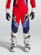 Alpinestars jeugd Supertech Dyna broek, vuurrode en donkerblauwe motorcrossbroek, atletische pasvorm, met witte laarzen.