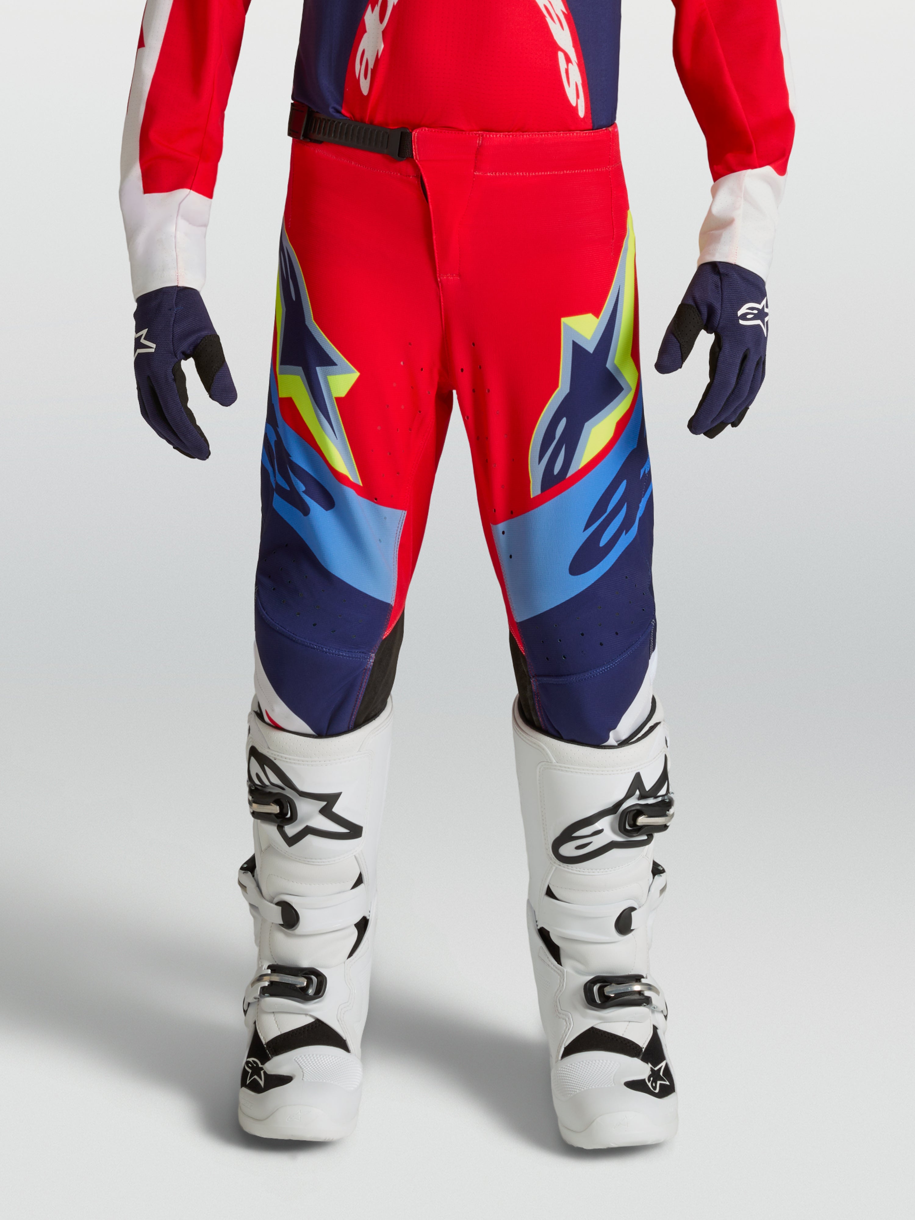 Alpinestars jeugd Supertech Dyna broek, vuurrode en donkerblauwe motorcrossbroek, atletische pasvorm, met witte laarzen.